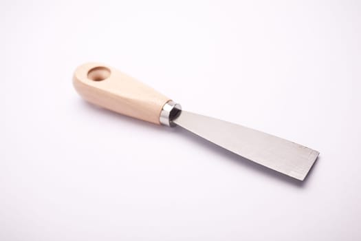 Putty knife with wooden handle on natural light background and a soft shadow