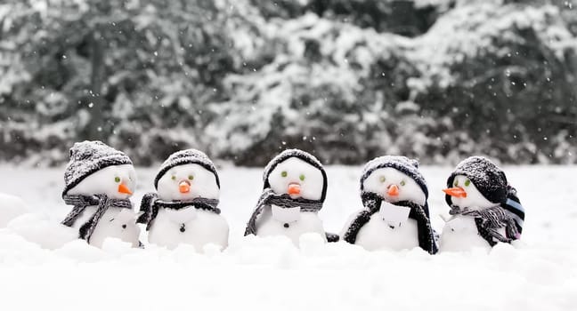 Little snowmen in a group carol singing in the snow
