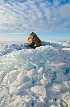 Big stone in the ice on the Baltic Sea coas