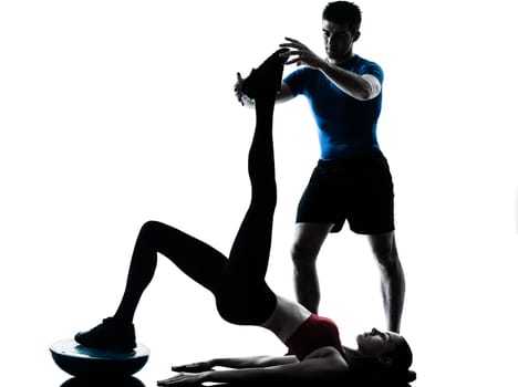 personal trainer man coach and woman exercising abdominals push ups on bosu silhouette  studio isolated on white background
