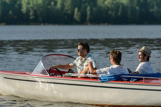 Young men driving speed boat enjoying sunshine