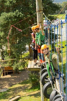 Adventure park visitors climbing on rope ladder adrenalin leisure time