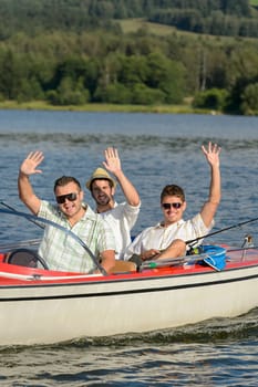 Cheerful young men sitting in motorboat enjoying sunshine