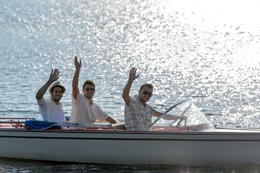 Three waving young men silhouette driving powerboat