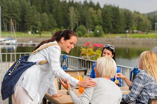 Woman arriving at outdoor restaurant terrace to her girl friends