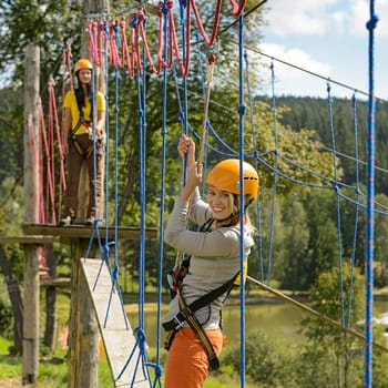 Smiling woman having fun in adventure park rope ladder