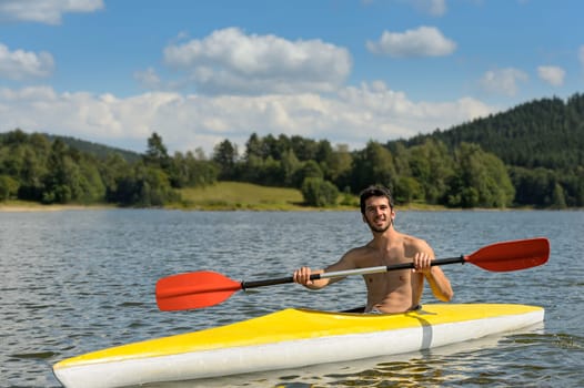 Young sportsman kayaking on sunny day on lake