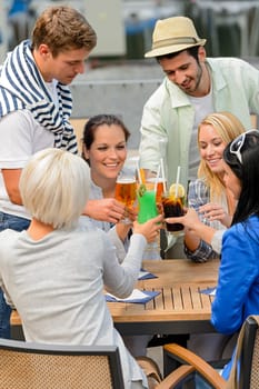 Group of cheerful young people toasting with cocktails outdoor terrace