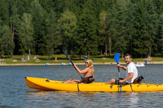Young couple on summer weekend kayaking on pond