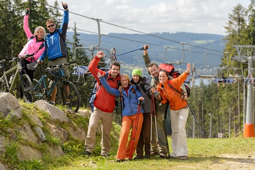 Cheering hikers with raised arms at peak of the mountain