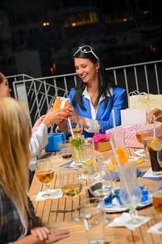 Young woman receiving birthday gifts terrace bar night out