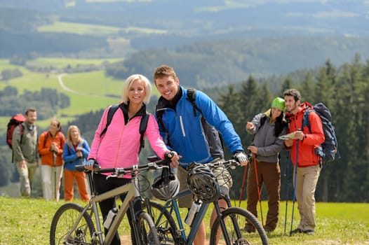 Sporty cyclist couple and hikers posing during springtime weekend