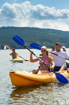Young friends kayaking in summertime on lake holiday