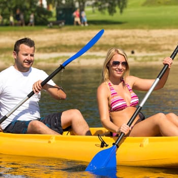 Young couple kayaking summertime in the sunshine vacation