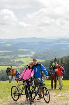 Posing cyclist couple on the mountain top with bikes