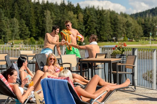 Young group of friends enjoying summertime drinking and sunbathing