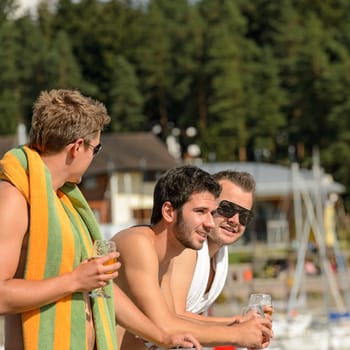 Young guys holding glasses talking at beach