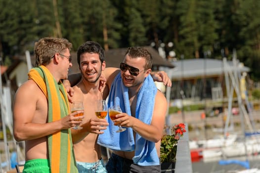 Young guys toasting with beer enjoying summer in swimsuits