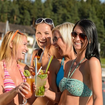 Young women in bikinis having fun with cocktails during summer