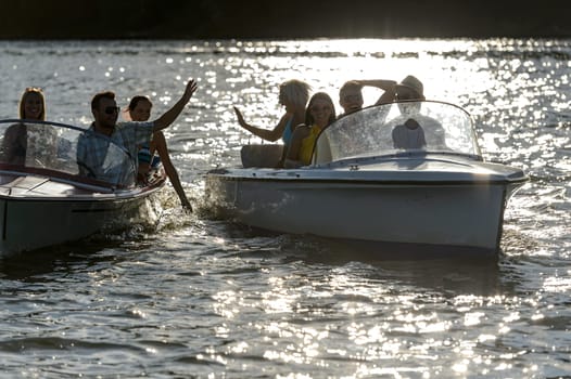 Silhouette of young people enjoying summer motorboat on lake