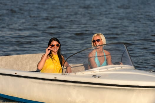 Young women in sunglasses sitting in motorboat driving