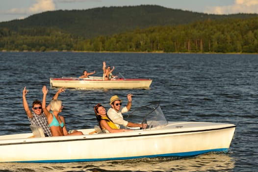 Group of cheerful friends racing with motorboats on river
