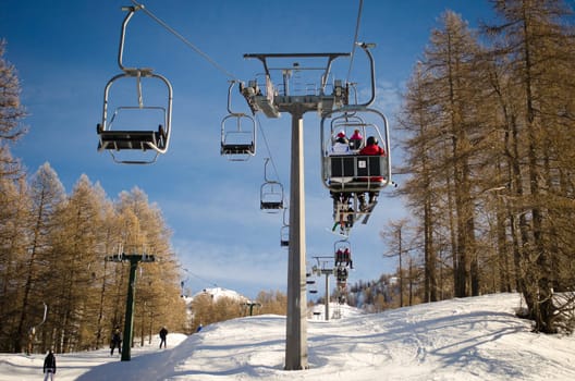People and skiers on chairlift (aerial lift) and skilift in sunny day