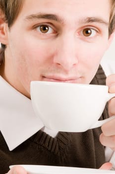 Side head and shoulders shot of a young man drinking from a white cup against a white background