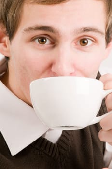 Side head and shoulders shot of a young man drinking from a white cup against a white background
