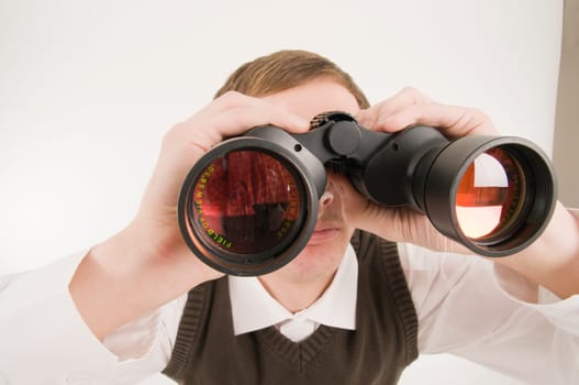 Frontal and extreme wide-angle shot of a young man with binoculars towards the camera against a white background