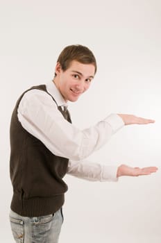 Side torso shot of a young man in jeans,white shirt and brown vestover,holding a virtual non-existent cardboard box against a white background and looking at the camera with a smile