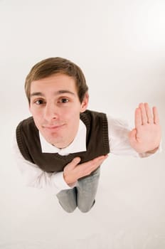 wide-angle top view of a young man in front of a white background in a white shirt and brown vestover,his hand raised in oath looking into the camera