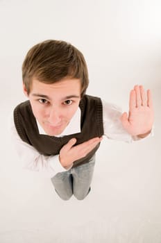wide-angle top view of a young man in front of a white background in a white shirt and brown vestover,his hand raised in oath looking into the camera