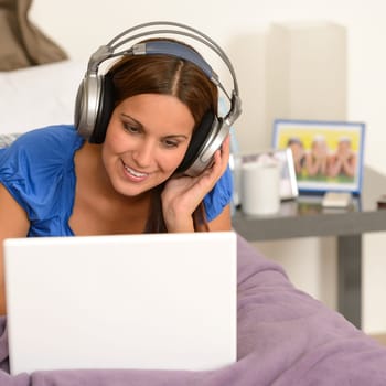 Teenage girl surfing on internet with laptop and headphones