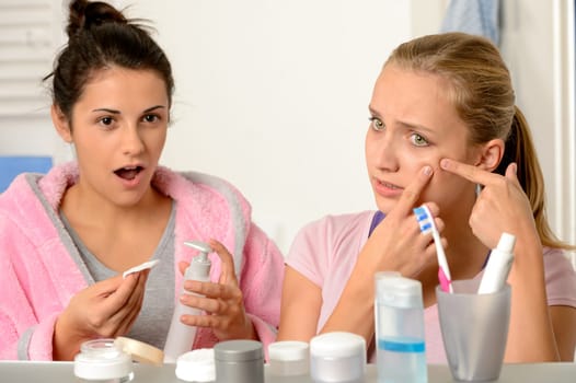 Young teenager with acne problem in the bathroom with friend