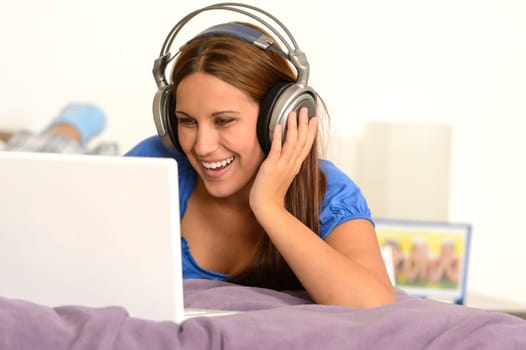Young girl watching movie on laptop lying on bed