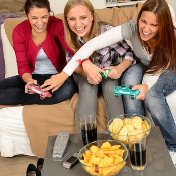 Laughing teenage girls playing with video game with consoles