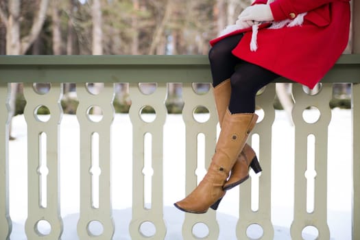 Young woman legs with boots at terrace boundary
