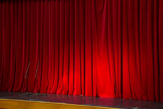 Lighted up red stage curtain and wait performer