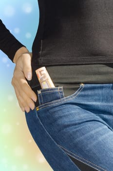 Roll of fifty euro banknotes in side pocket of female jeans on colorful blured background