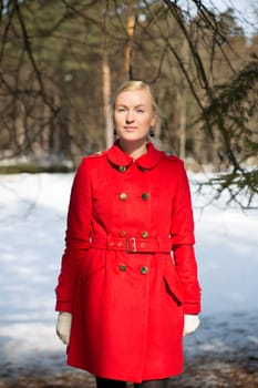 Young woman in red coat posing under spruce