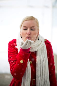 Young woman blowing snow cereal from her hand