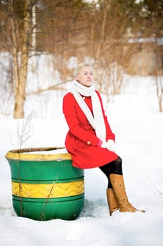 Young woman sitting on empty big painted flowerpot