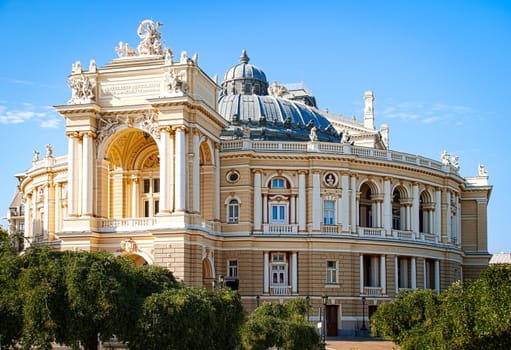 Odesa opera theatre with blue sky in background and trees in foreground (Odesa or Odessa, Ukraine)