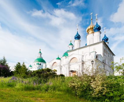 Spaso-Jakovlevskij monastery with blue cloudy sky in background and green grass in foreground. Rostov, Golden ring, Russia.