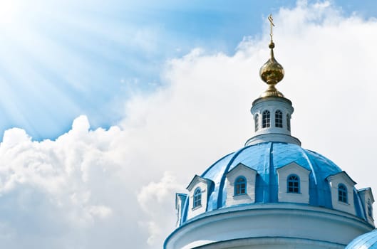Blue dome of beautiful old russian church with cloudy sky in background.