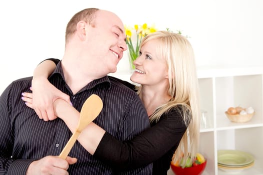 Romantic couple preparing a meal together in the kitchen standing in a close embrace smiling into each others eyes