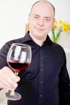 Attractive mature man raising his glass to the camera in a toast of celebration , as an acknowledgement or in a polite greeting