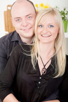 Attractive married couple standing close together posing for a portrait looking at the camera and smiling