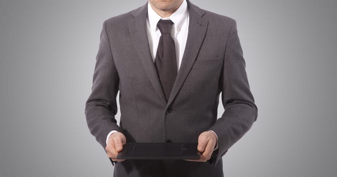 business man with touch tablet in hands, grey background.